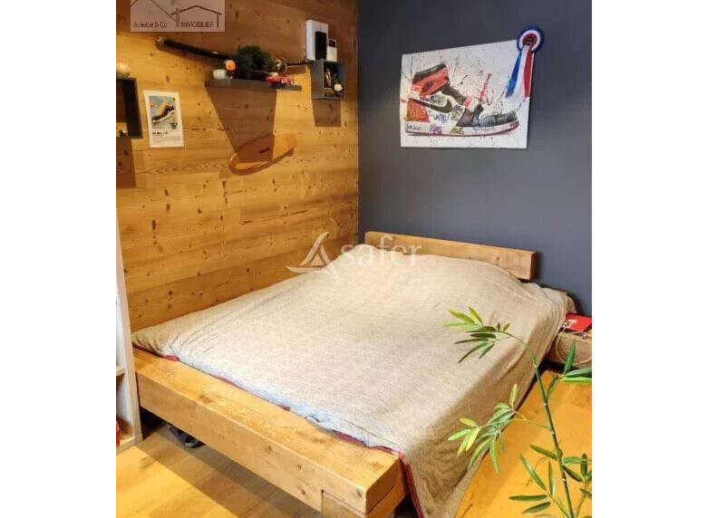 Discover a cozy bedroom with a unique wooden bed frame and a stylish painting.