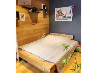 Discover a cozy bedroom with a unique wooden bed frame and a stylish painting.