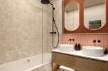 Modern bathroom with double sinks, a bathtub, and a walk-in shower.