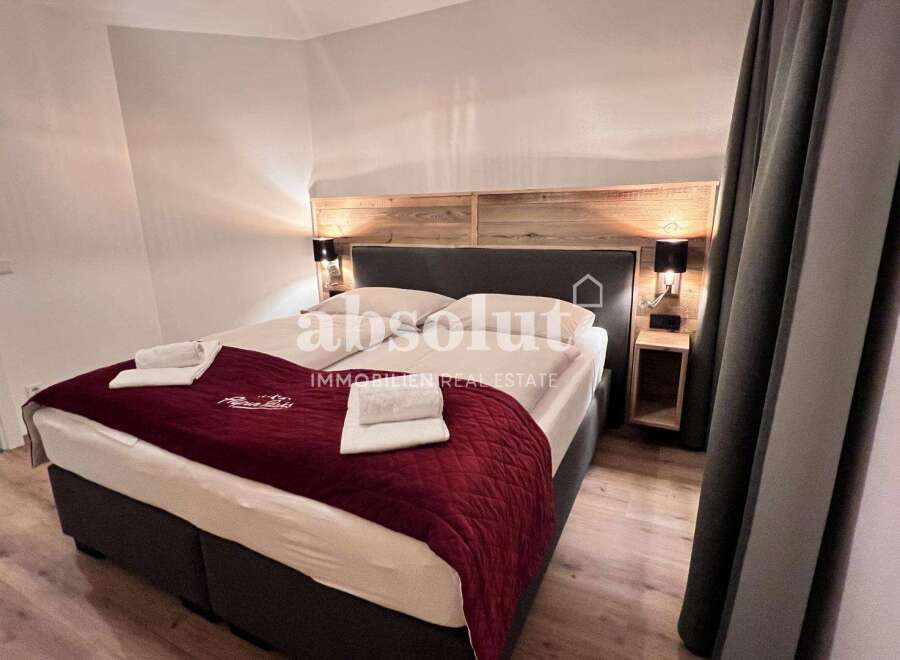 Discover a cozy bedroom featuring a comfortable bed with a stylish red quilt.