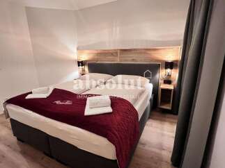 Discover a cozy bedroom featuring a comfortable bed with a stylish red quilt.