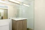 This modern bathroom boasts a sleek glass shower enclosure, contemporary wood-look vanity, and stylish chrome fixtures.