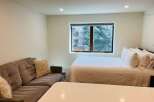 This cozy studio apartment offers a comfortable living space with a plush sofa and a queen-sized bed.
