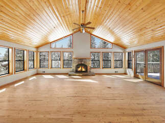This stunning property boasts a spacious, open-plan living area with soaring ceilings and expansive windows offering breathtaking views of the snowy landscape.