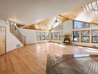 This stunning home boasts a spacious open floor plan with gleaming hardwood floors and a cozy stone fireplace, perfect for entertaining guests or relaxing by the fire.