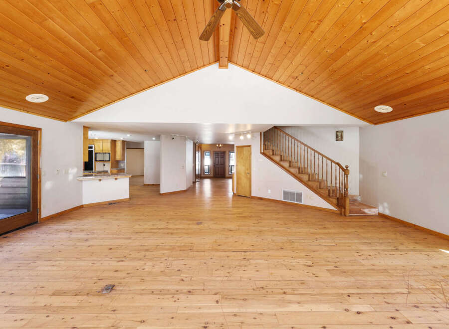 This stunning property boasts a spacious open-plan living area with gleaming hardwood floors and a soaring wood-paneled ceiling, creating a warm and inviting atmosphere.