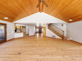 This stunning property boasts a spacious open-plan living area with gleaming hardwood floors and a soaring wood-paneled ceiling, creating a warm and inviting atmosphere.