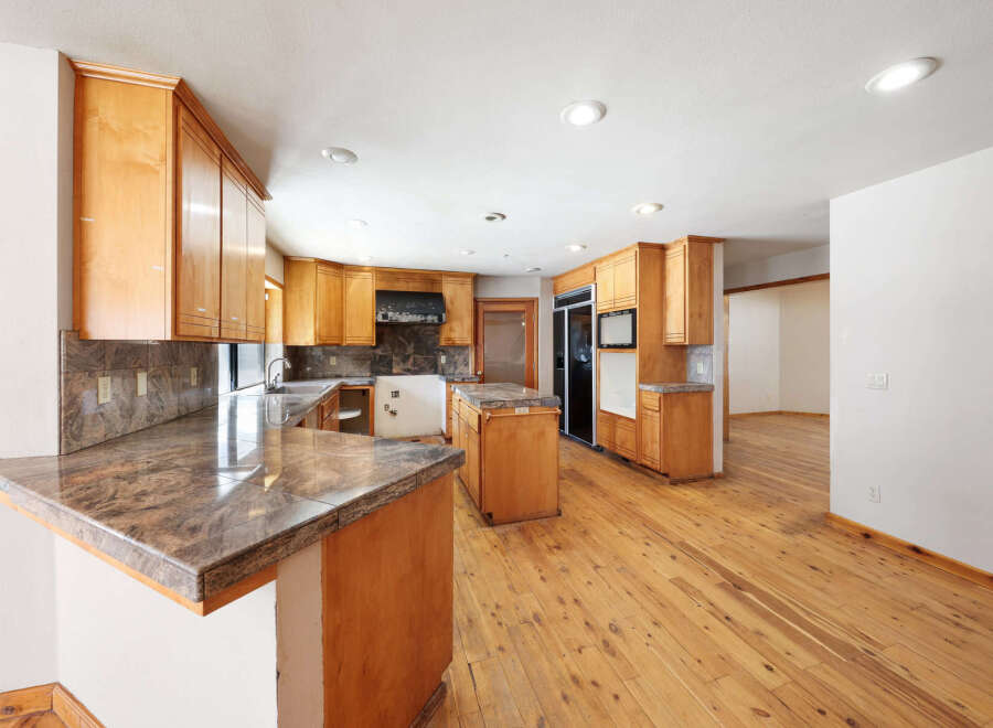 This stunning kitchen boasts beautiful wood flooring and granite countertops, creating a warm and inviting atmosphere.