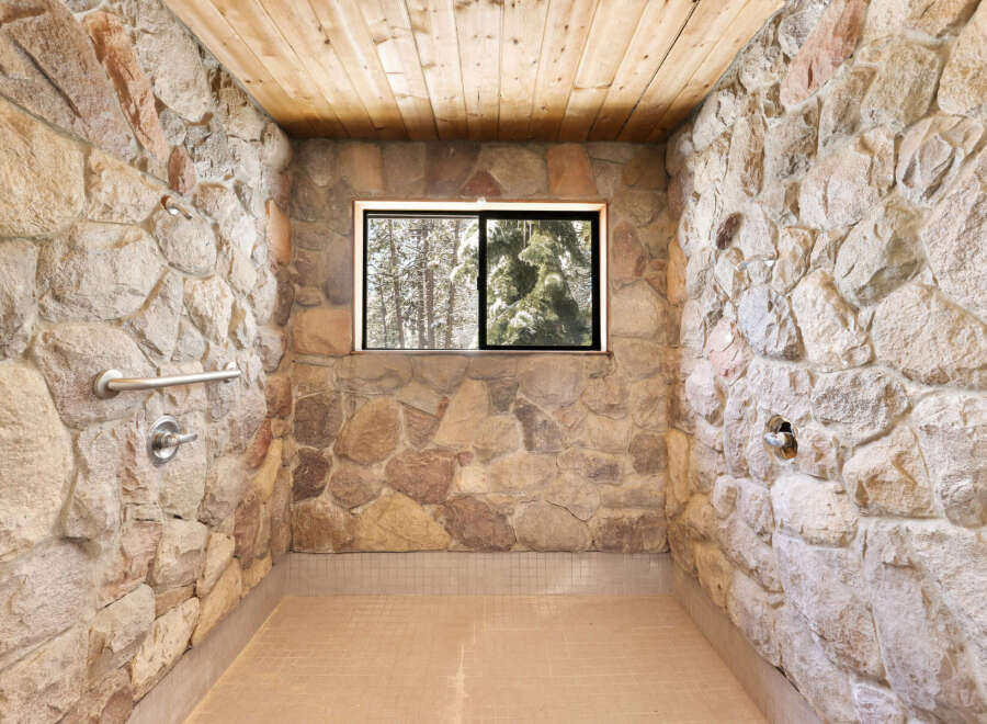 This rustic shower boasts a unique stone wall design, creating a natural and charming atmosphere.