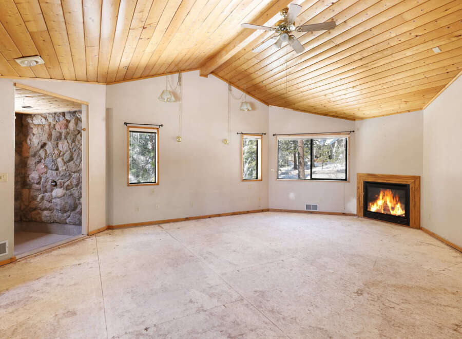 This spacious room boasts a stunning wood-paneled ceiling, a cozy fireplace, and large windows offering abundant natural light.