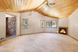 This spacious room boasts a stunning wood-paneled ceiling, a cozy fireplace, and large windows offering abundant natural light.