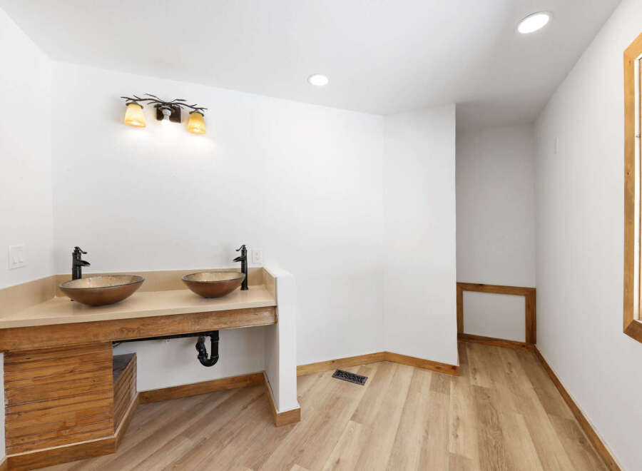 This stunning bathroom boasts dual sinks with modern bronze faucets, nestled into a custom wooden vanity.