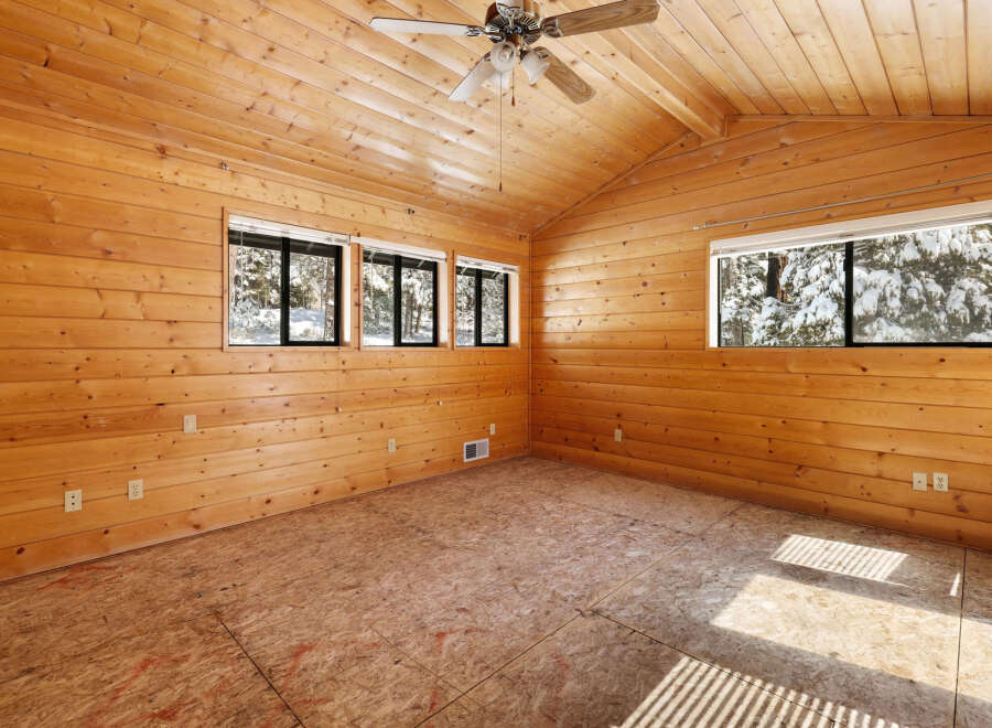 This stunning log cabin boasts a spacious interior with vaulted ceilings and large windows offering breathtaking views of the snowy landscape.