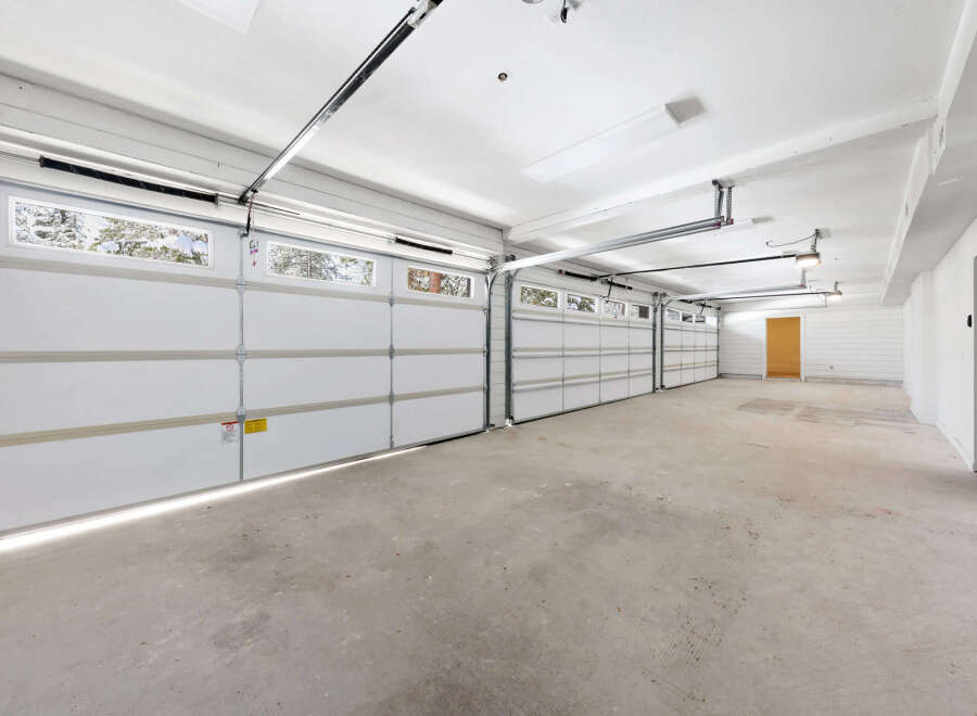 This spacious garage boasts three large white doors, offering ample room for multiple vehicles.