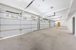 This spacious garage boasts three large white doors, offering ample room for multiple vehicles.