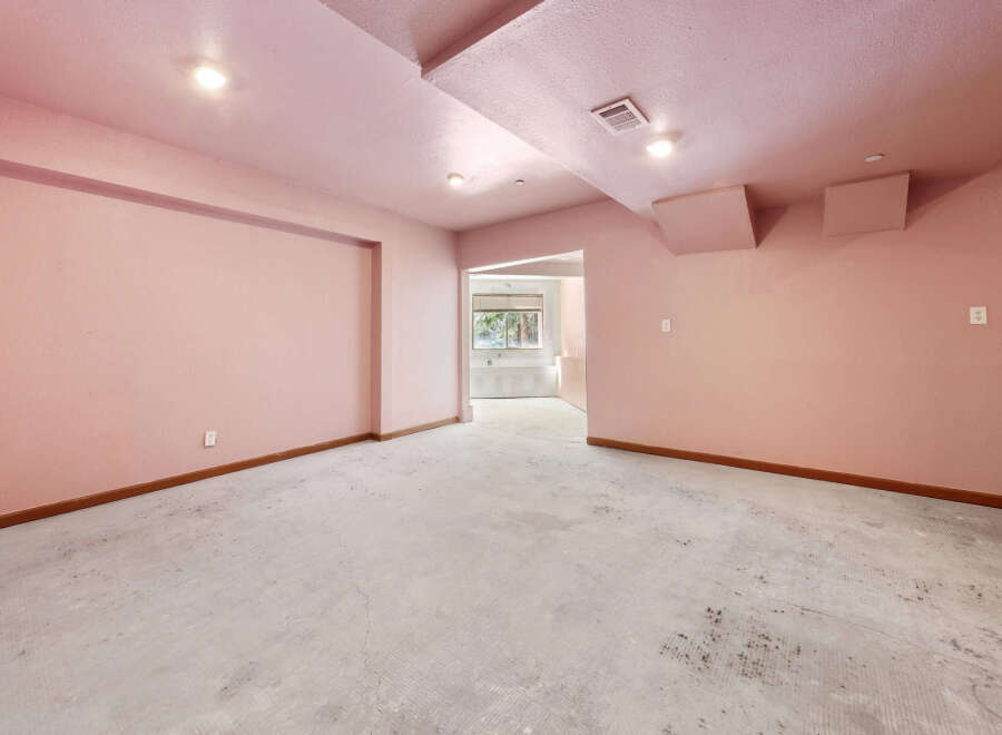 This unfinished basement boasts a spacious layout with light pink walls and a concrete floor, offering endless possibilities for customization.