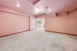 This unfinished basement boasts a spacious layout with light pink walls and a concrete floor, offering endless possibilities for customization.