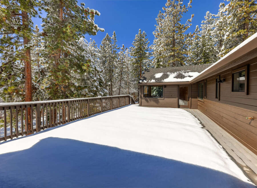 This stunning mountain home boasts a spacious deck perfect for enjoying the snowy landscape.