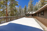 This stunning mountain home boasts a spacious deck perfect for enjoying the snowy landscape.
