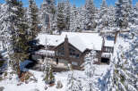 This stunning mountain home boasts a spacious layout with multiple levels, large windows offering breathtaking views, and a sizable deck perfect for enjoying the snowy landscape.