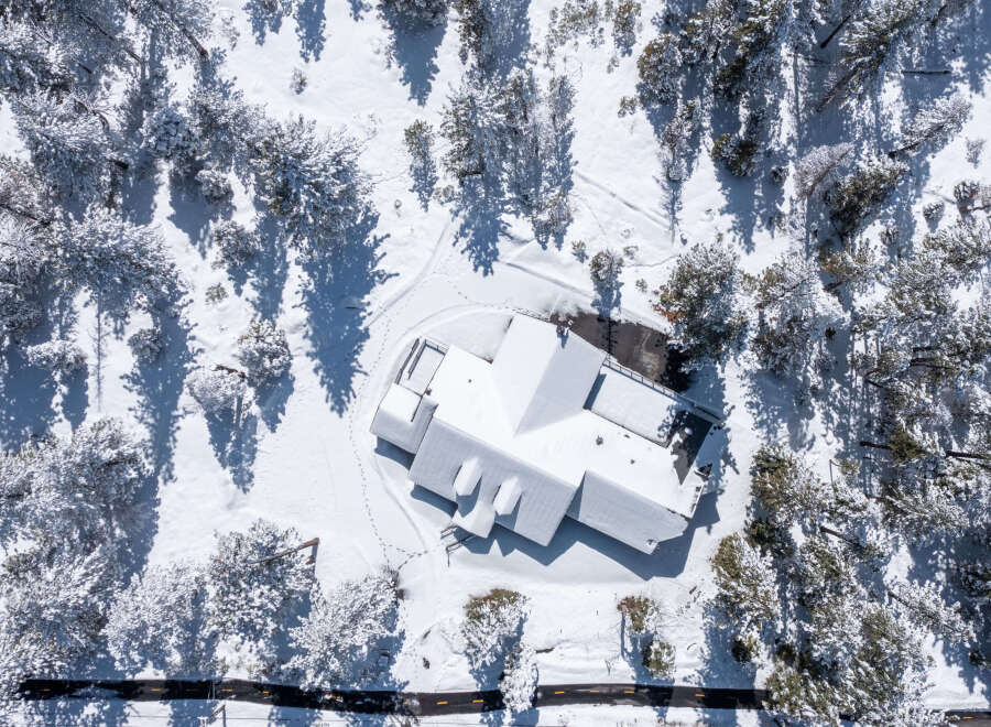 This stunning property boasts a spacious house with a unique architectural design, perfectly nestled amidst a snow-covered pine forest.