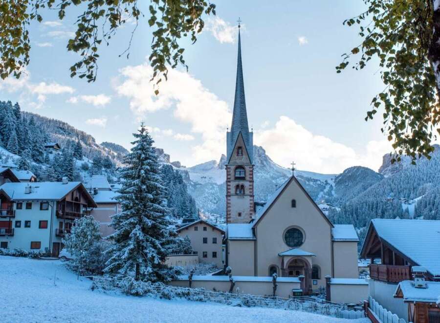 Nestled in a snow-covered mountain village, this charming church boasts a tall, pointed spire and a tranquil atmosphere.