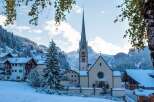Nestled in a snow-covered mountain village, this charming church boasts a tall, pointed spire and a tranquil atmosphere.