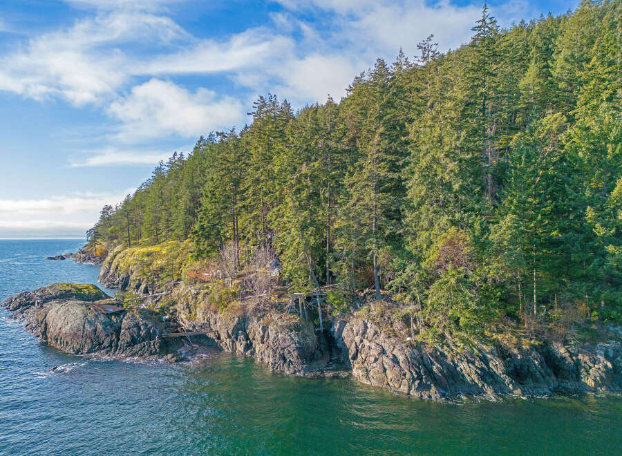 Discover this breathtaking waterfront property nestled amidst lush evergreen forests.