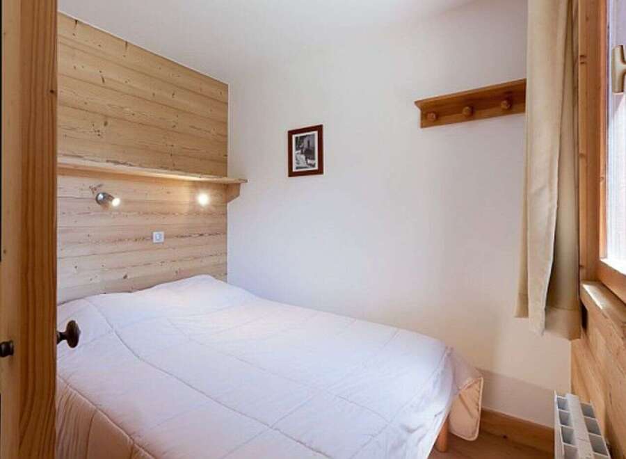 Cozy bedroom with wooden walls and a comfortable double bed.