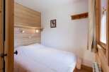Cozy bedroom with wooden walls and a comfortable double bed.