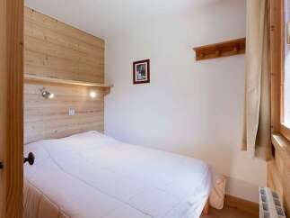 Cozy bedroom with wooden walls and a comfortable double bed.
