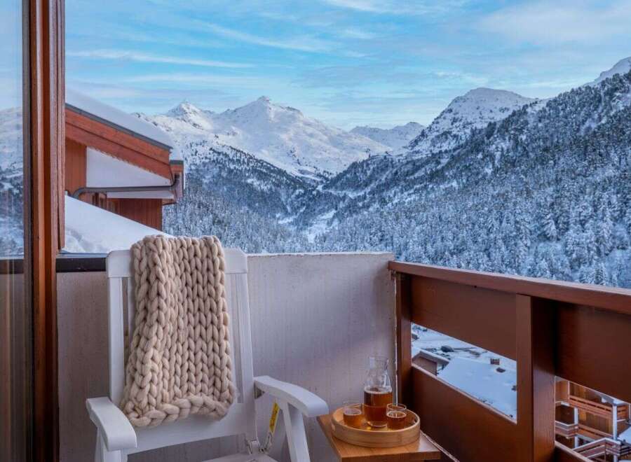 Enjoy breathtaking mountain views from your private balcony, complete with cozy seating and a warm knit throw.