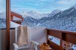 Enjoy breathtaking mountain views from your private balcony, complete with cozy seating and a warm knit throw.