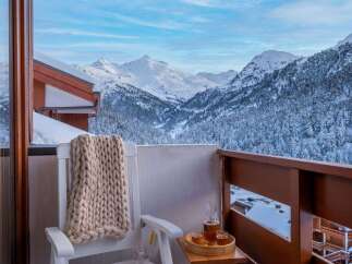 Enjoy breathtaking mountain views from your private balcony, complete with cozy seating and a warm knit throw.