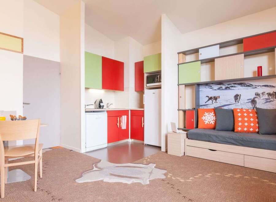 This modern apartment boasts a stylish kitchenette with red and green cabinets, perfect for a quick meal.
