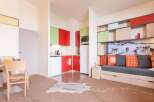 This modern apartment boasts a stylish kitchenette with red and green cabinets, perfect for a quick meal.