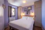 This cozy hotel room features a comfortable double bed, ample closet space, and tasteful wall art.