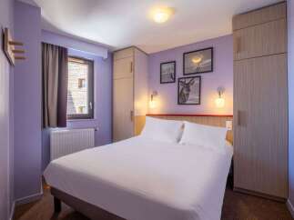 This cozy hotel room features a comfortable double bed, ample closet space, and tasteful wall art.