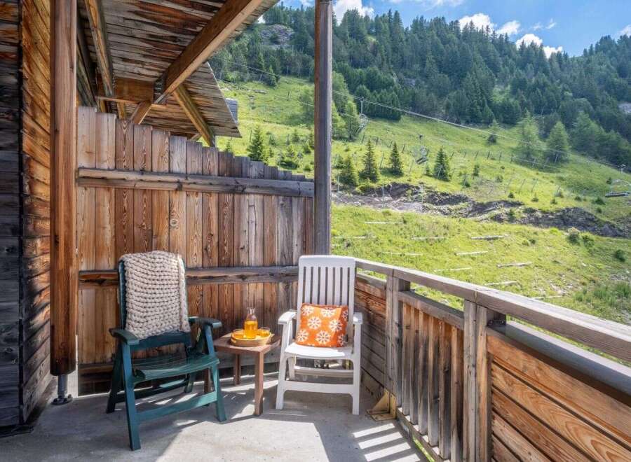Enjoy breathtaking mountain views from your private balcony, complete with comfortable seating and a small table.