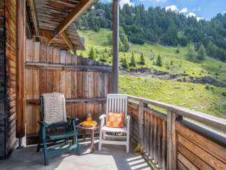 Enjoy breathtaking mountain views from your private balcony, complete with comfortable seating and a small table.