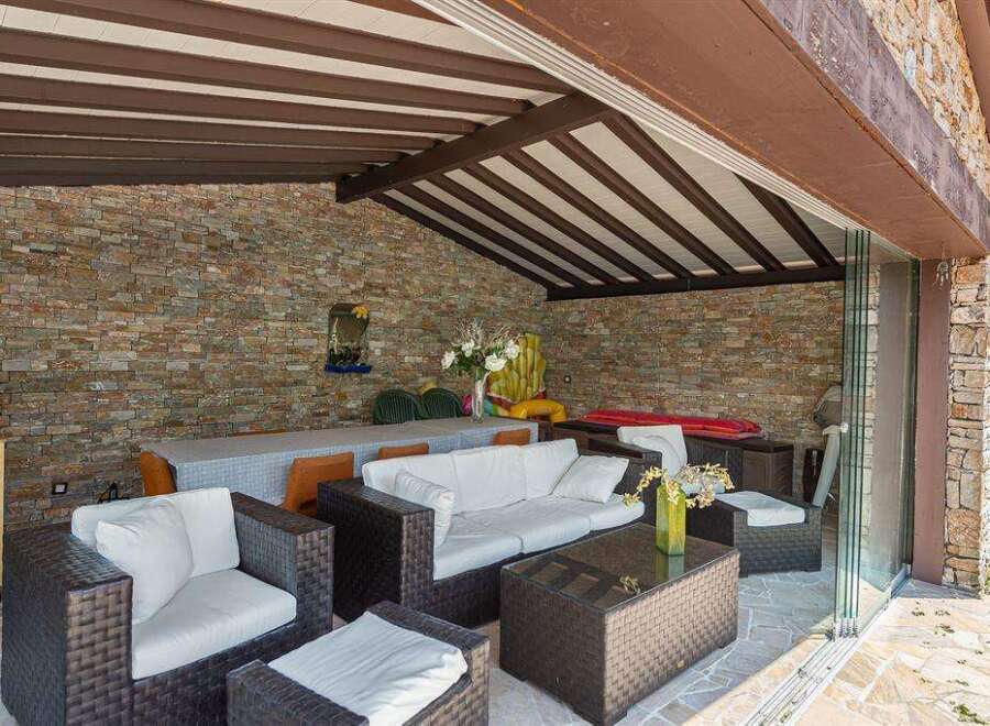 This stunning property boasts a luxurious outdoor patio, complete with a cozy seating area and a beautiful stone wall.