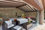 This stunning property boasts a luxurious outdoor patio, complete with a cozy seating area and a beautiful stone wall.