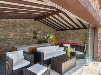 This stunning property boasts a luxurious outdoor patio, complete with a cozy seating area and a beautiful stone wall.