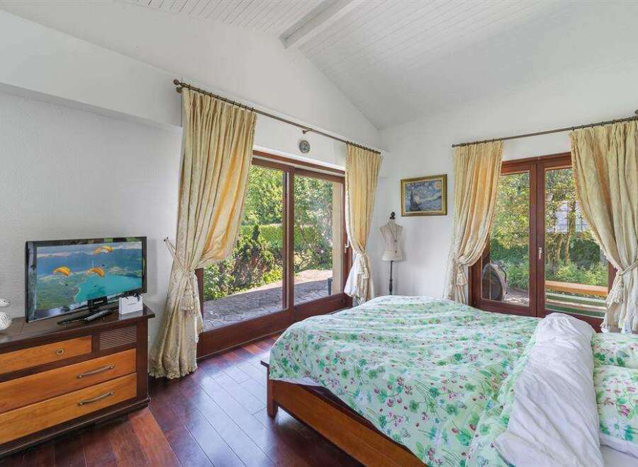 This stunning bedroom boasts a tranquil atmosphere with large windows offering picturesque garden views.