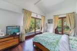 This stunning bedroom boasts a tranquil atmosphere with large windows offering picturesque garden views.