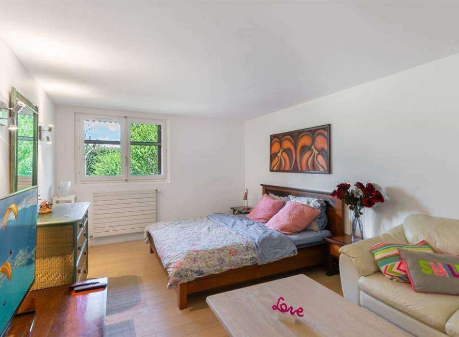 Cozy bedroom with a double bed, flat-screen TV, and plenty of natural light from large windows.