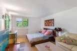 Cozy bedroom with a double bed, flat-screen TV, and plenty of natural light from large windows.