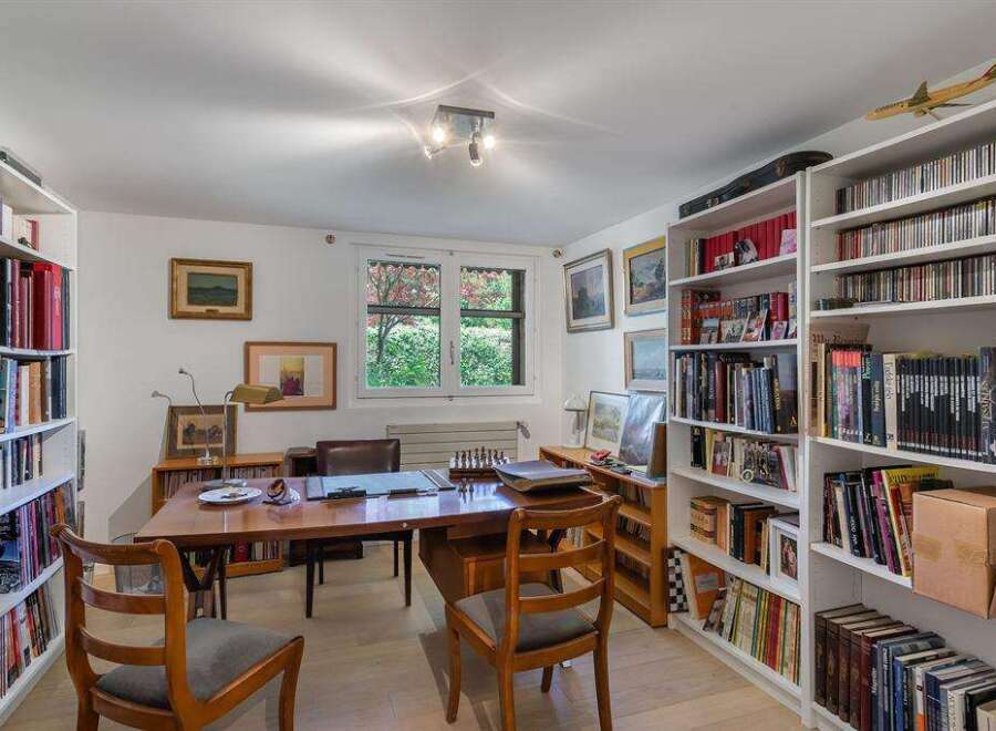 This charming home office boasts built-in bookshelves, ample natural light, and a spacious desk perfect for work or study.