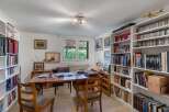 This charming home office boasts built-in bookshelves, ample natural light, and a spacious desk perfect for work or study.