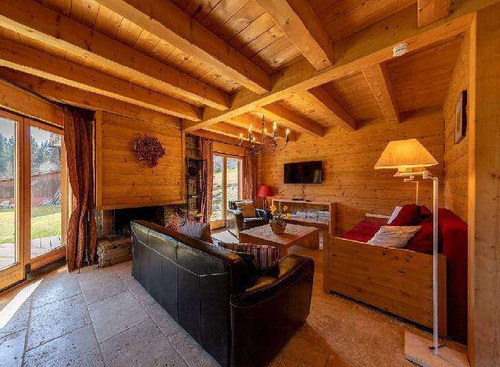 Cozy wooden chalet with large windows offering stunning mountain views.